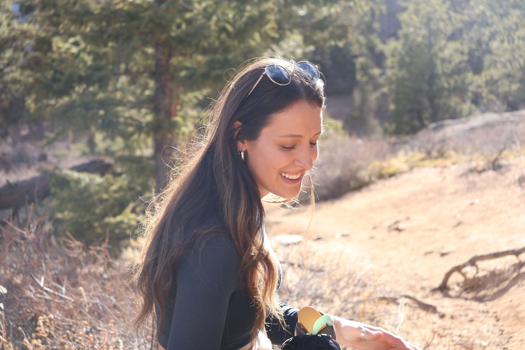 A woman smiling in golden light on a sunlit trail during a portrait session